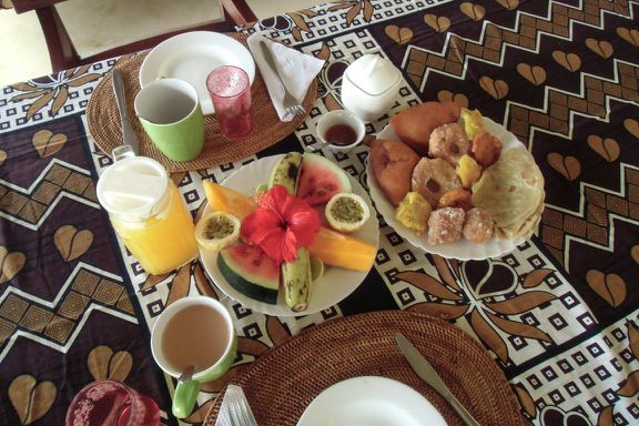 Ein Swahili-Frühstück: Frisch gepresster Saft, Chai (eine Art Tee), Obst, Gebäck, Süsskartoffeln und Chapati (Fladenbrot).