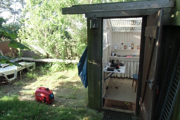 Das eingerichtete Shack mit Honda-Moppel und Mülltüte vor der Tür.