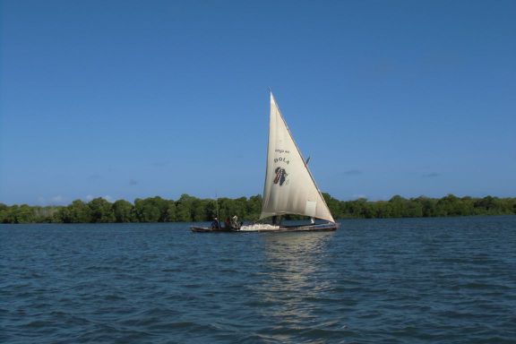 Eine Dhau, die Baumaterial vom Steinbruch Manda transportiert und tief im Wasser liegt.