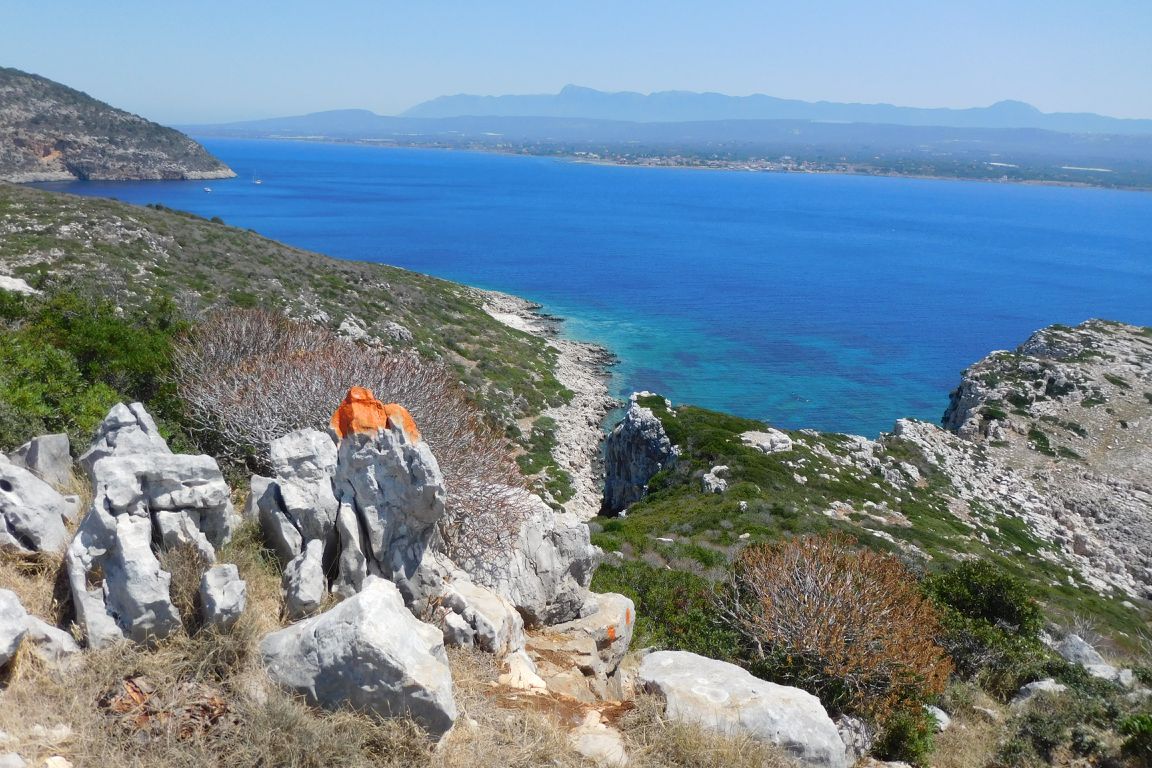 Blick nach Marathopolis. Die orangen Markierungen weisen den Weg auf einem steinigen Naturpfad über die Insel